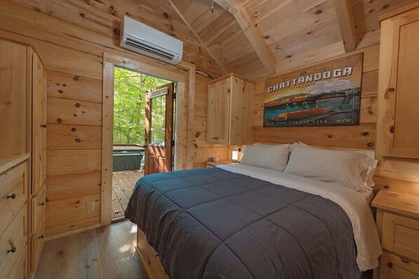A wooden cabin room with a bed, a poster, and an air conditioning unit.
