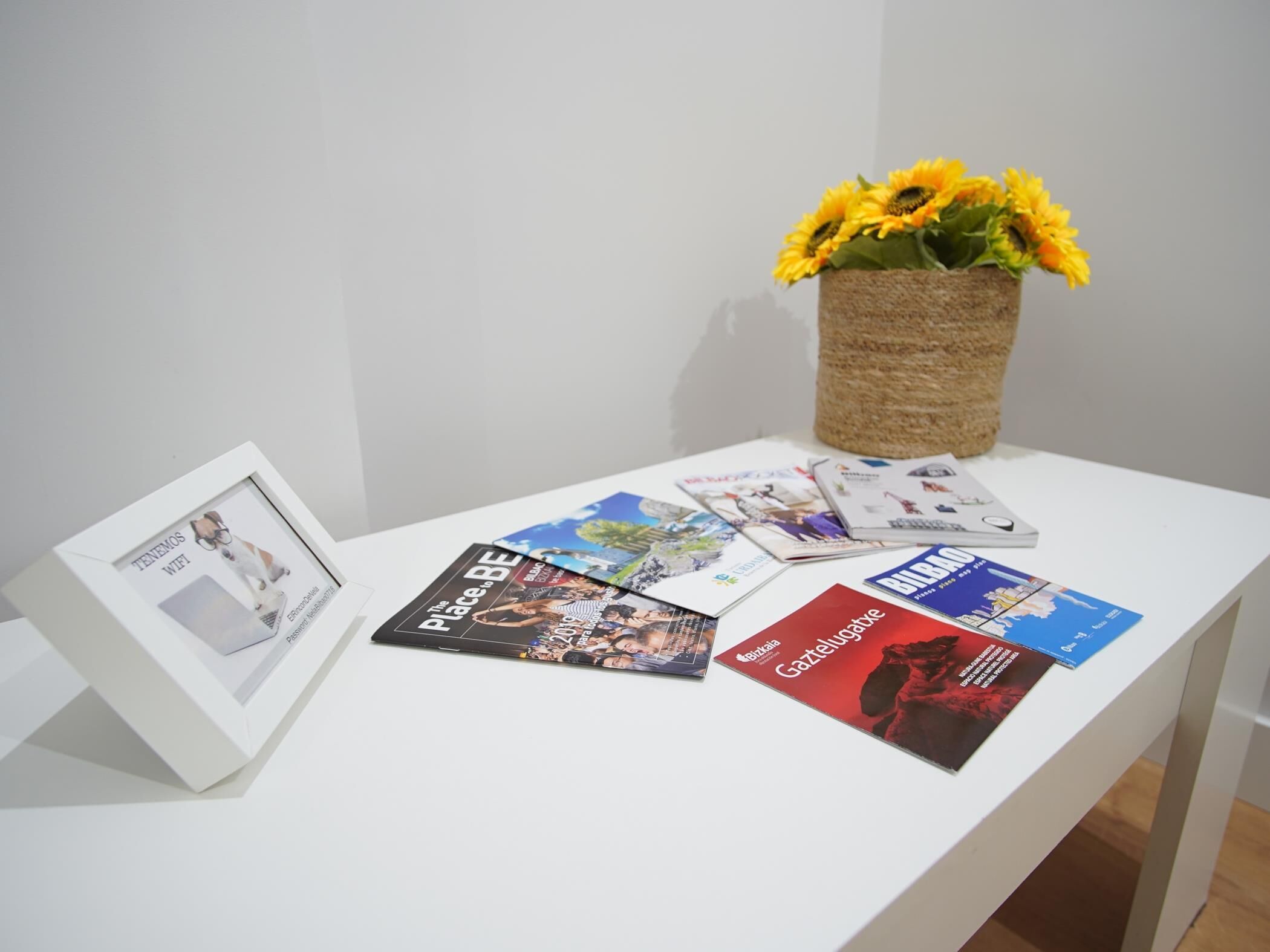 Una mesa blanca con revistas y un marco con una fotografía.