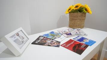 Una mesa blanca con revistas y un marco con una fotografía.