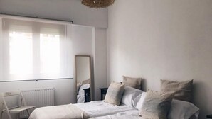 Un dormitori minimalista amb dos llits, un mirall gran i un radiador.