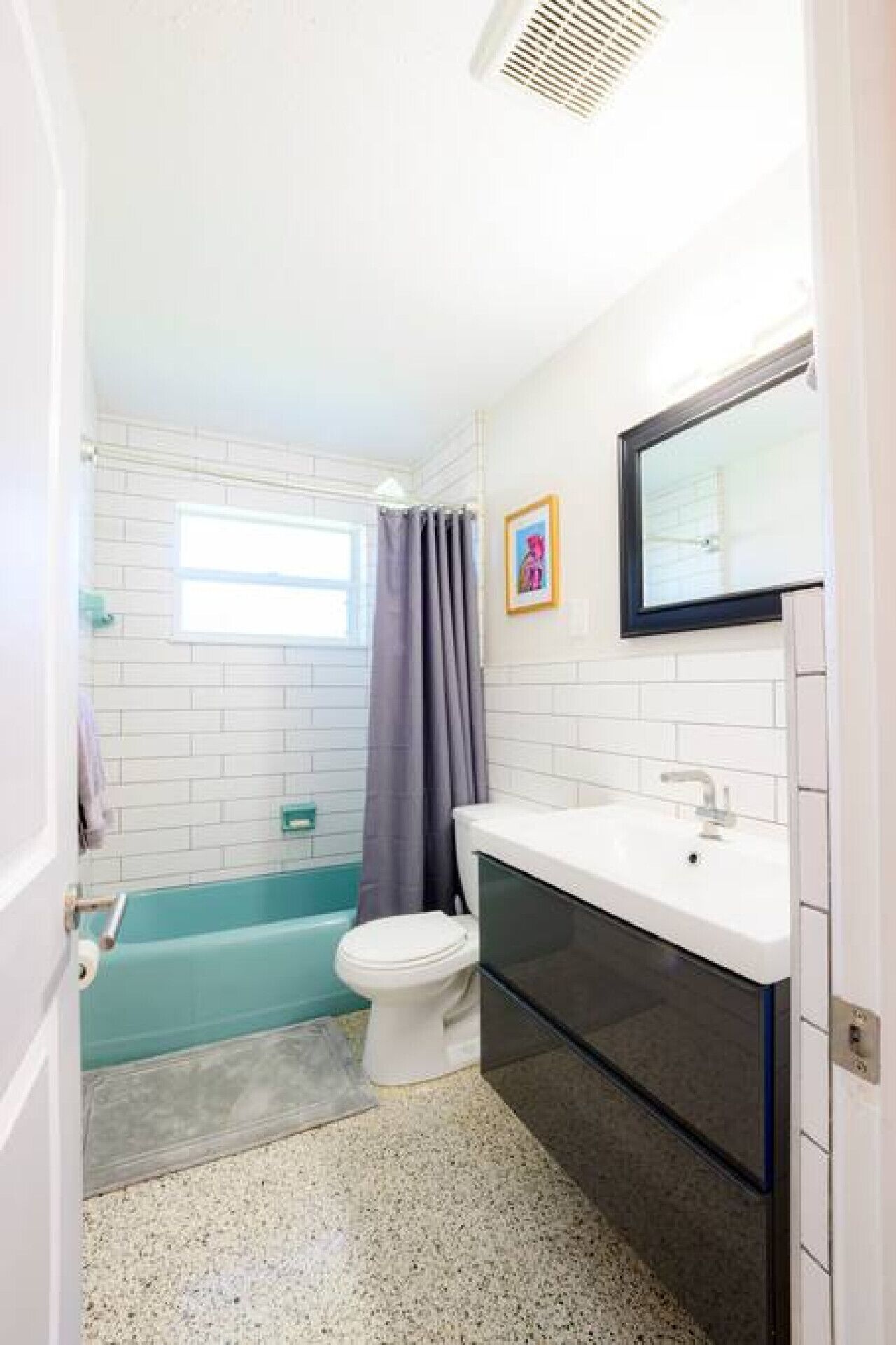 Une salle de bain avec des toilettes blanches, une baignoire et un lavabo avec un miroir.