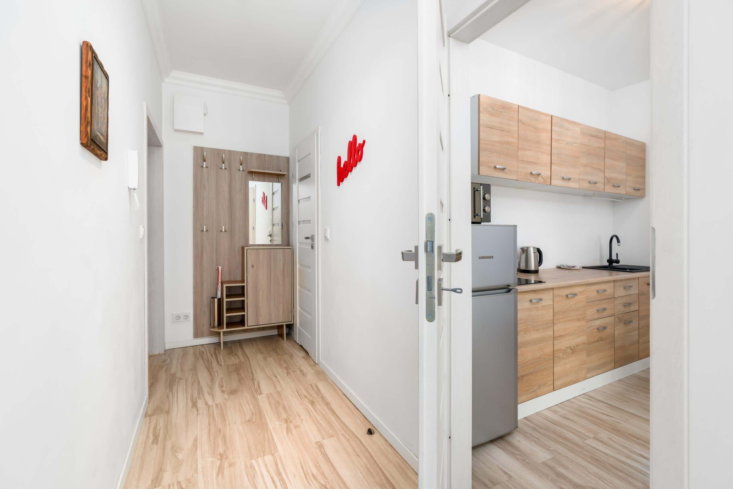 A modern kitchen with wooden cabinets, a refrigerator, and a kettle.