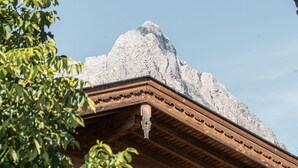 A wooden chalet with a stone roof, wooden balcony, and a wooden fence in the foreground.