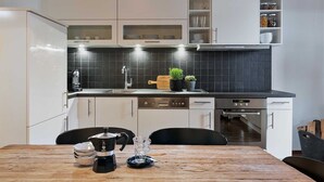 A modern kitchen with white cabinets, a black countertop, and a wooden dining table.