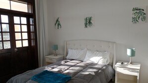 Ein Schlafzimmer mit einem Bett, zwei Nachttischen, einer Tür und einem Fenster.