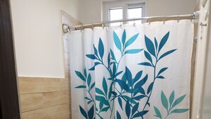 Ein Badezimmer mit Toilette, Waschbecken und einer Duschtasse mit Blätchenmuster.