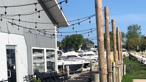 Un restaurant situé au bord de l’eau, doté d’une terrasse, d’un quai pour bateaux et illuminé de guirlandes lumineuses.