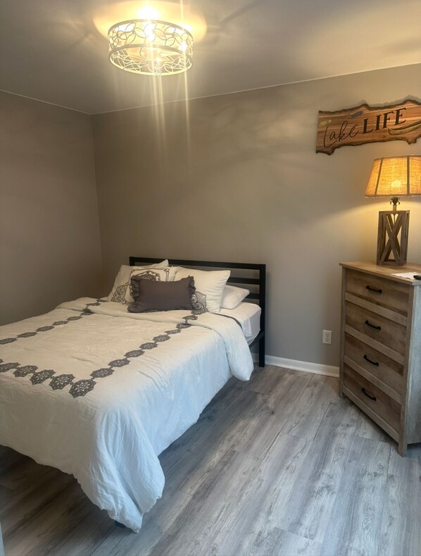 A bedroom with a bed, a nightstand, a lamp, and a wall decoration.