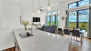 Une cuisine spacieuse avec un grand îlot central, un coin repas avec une table et des chaises, et un salon avec un canapé et un téléviseur.