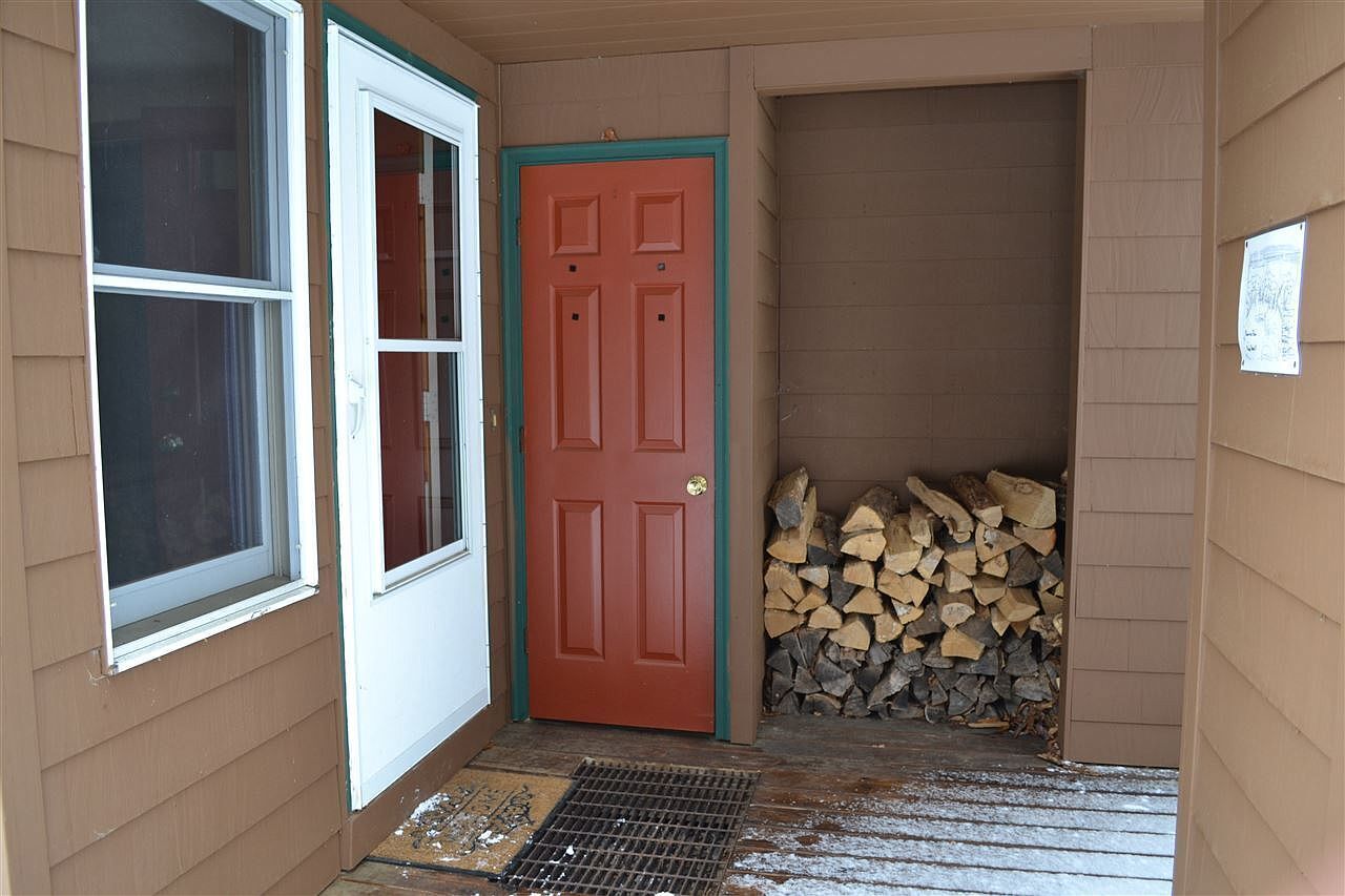 A wooden door with a red frame, a window, and a stack of firewood.