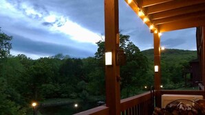 A wooden deck with a railing overlooking a forested area and a body of water. - Mountain Condo w Modern CabinStyle @Hunter&Windham (East Jewett)