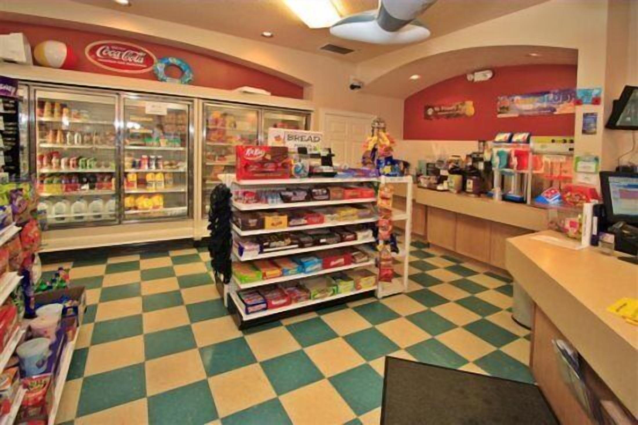 A store interior with a checkered floor, refrigerated display cases, and shelves stocked with various products.