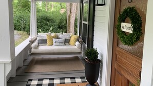 A porch with a white bench, black and white cushions, a welcome wreath, and a potted plant. - Renovated Cottage - Walk to Downtown Mentone (Mentone)