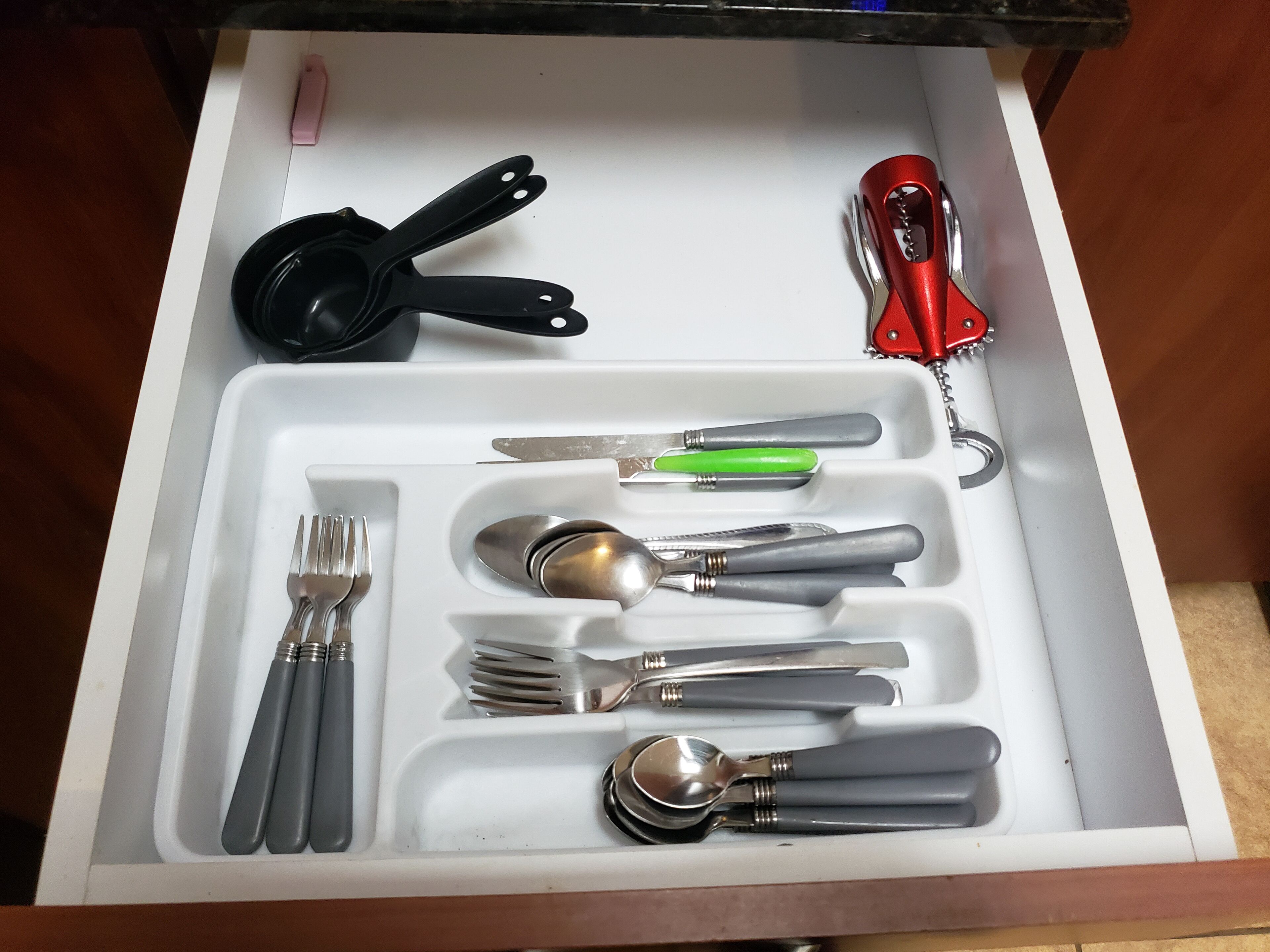 A drawer with various utensils neatly organized, including forks, spoons, and a knife.
