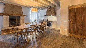 A spacious kitchen with a large wooden table and chairs, a fireplace, and a wooden door. - Apartment "Ontano" in Agriturismo Style with Wi-Fi, Garden, and Shared Pool (Desenzano)