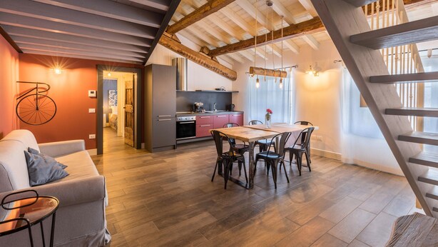 A modern interior with a dining area, kitchen, and staircase. - Modern Loft Apartment "Begonia" with Wi-Fi, Shared Garden & Pool (Desenzano)