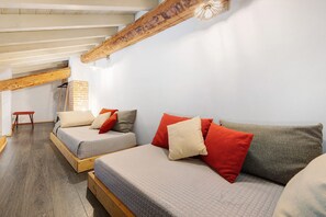 Una habitación con dos camas, un banco de madera y una pared de ladrillo.