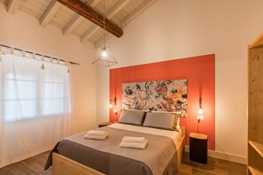 Un dormitorio con una cama, una gran obra de arte floral en la pared y techo de madera.