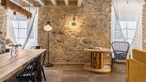 Un interno rustico con pareti in pietra a vista, un tavolo in legno e un tavolo rotondo di legno.
