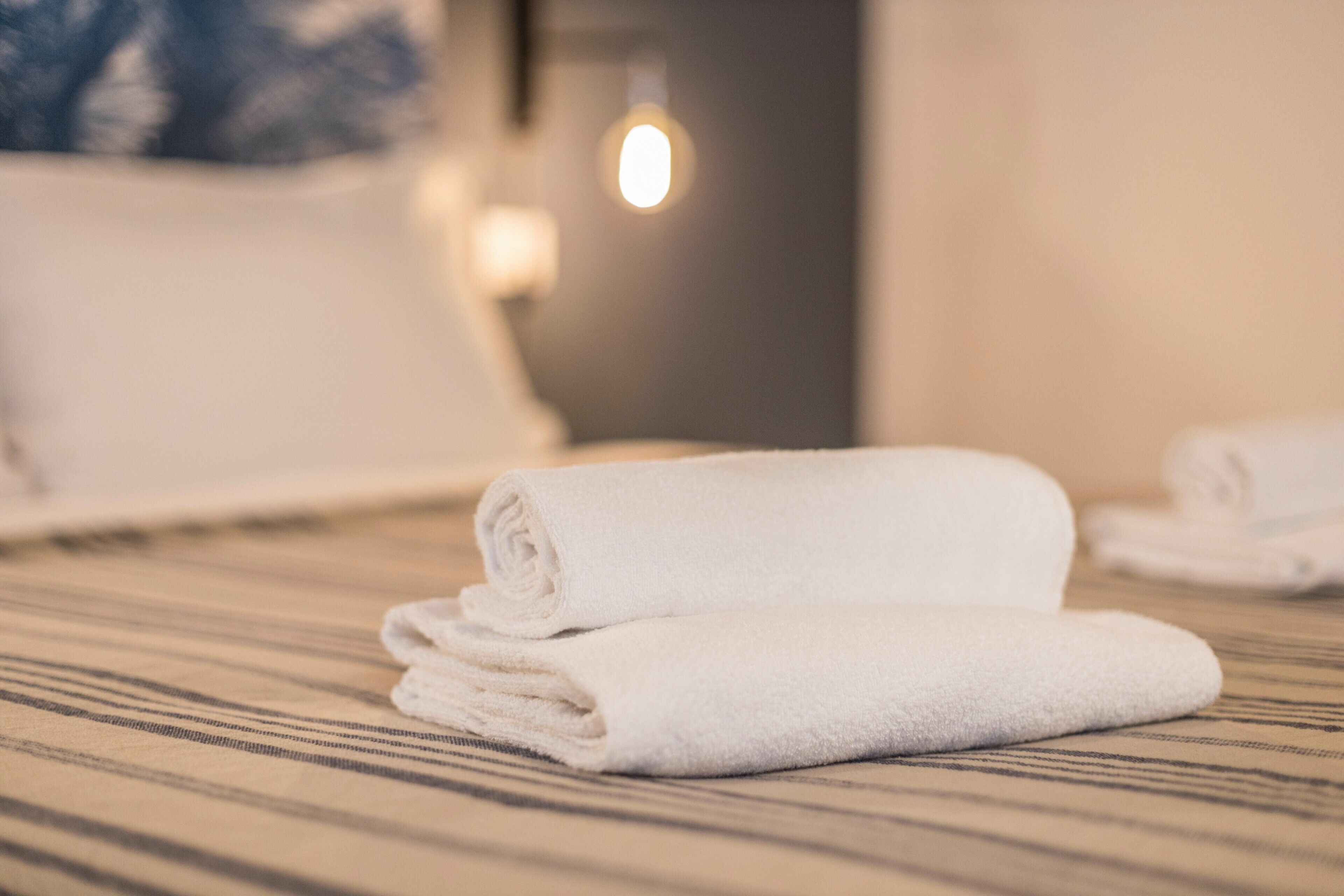Uma toalha branca dobrada sobre uma superfície listrada, provavelmente em um quarto de hotel.