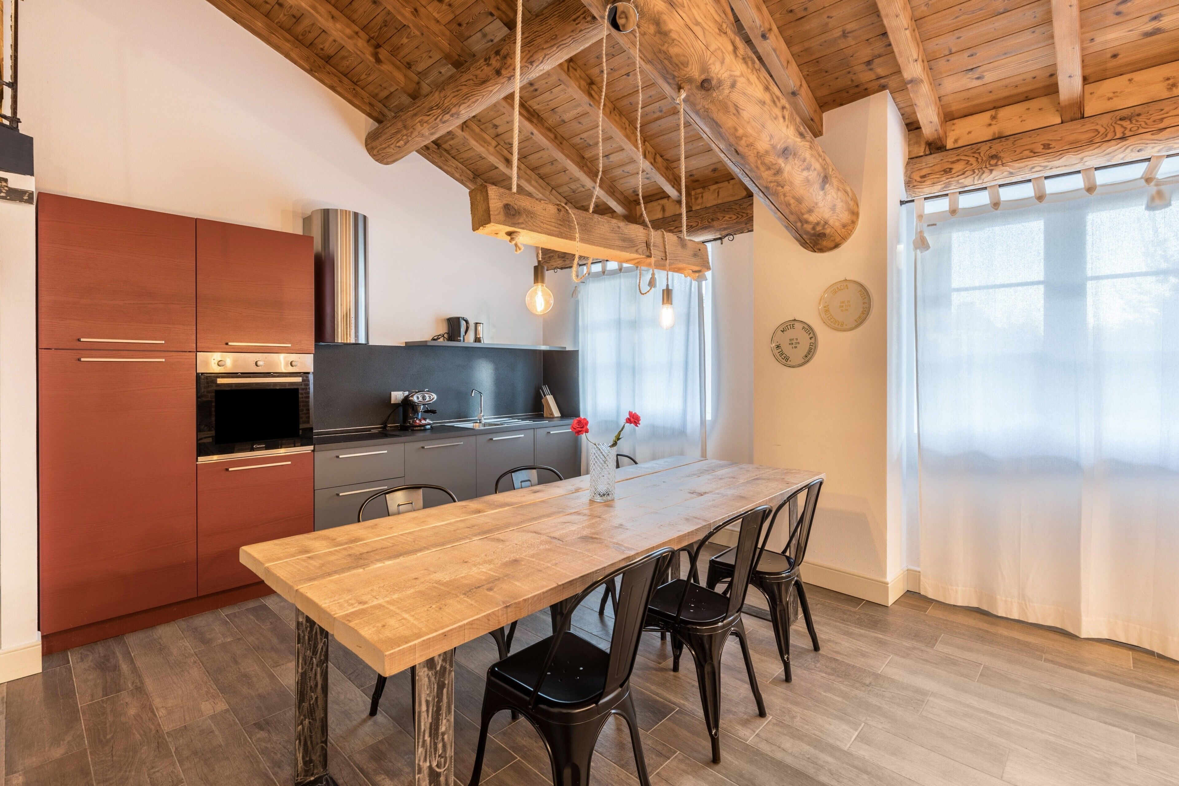 A modern kitchen with wooden beams, a wooden dining table, and black chairs.