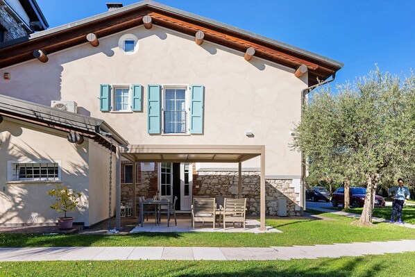 A house with a covered patio, a stone wall, and a tree.