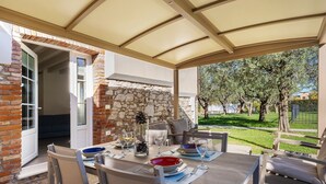 Un patio exterior con un muro de piedra, una mesa cubierta y sillas.