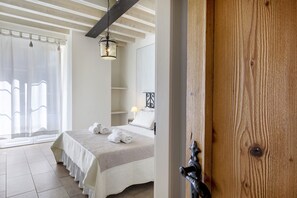 A bedroom with a bed, a bedside table, a lamp, and a window with curtains.