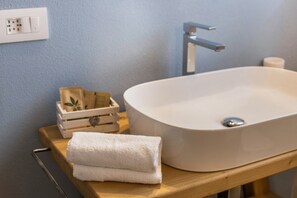 Une salle de bain avec un lavabo blanc, un plateau en bois, une serviette blanche, une caisse en bois et un mur bleu.