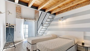 A bedroom with two beds, a wooden ceiling, a staircase, and a hanging light fixture. - Large Family Apartment "Rovere" with Wi-Fi, Shared Garden & Pool (Desenzano)