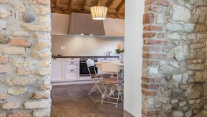 Une cuisine avec des armoires blanches, un plafond en bois et un luminaire suspendu.