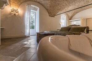 Ein Zimmer mit Backstein-Decke, einem Bett mit Kissen, einem Korbwannen-Korb und einer Wandleuchte.