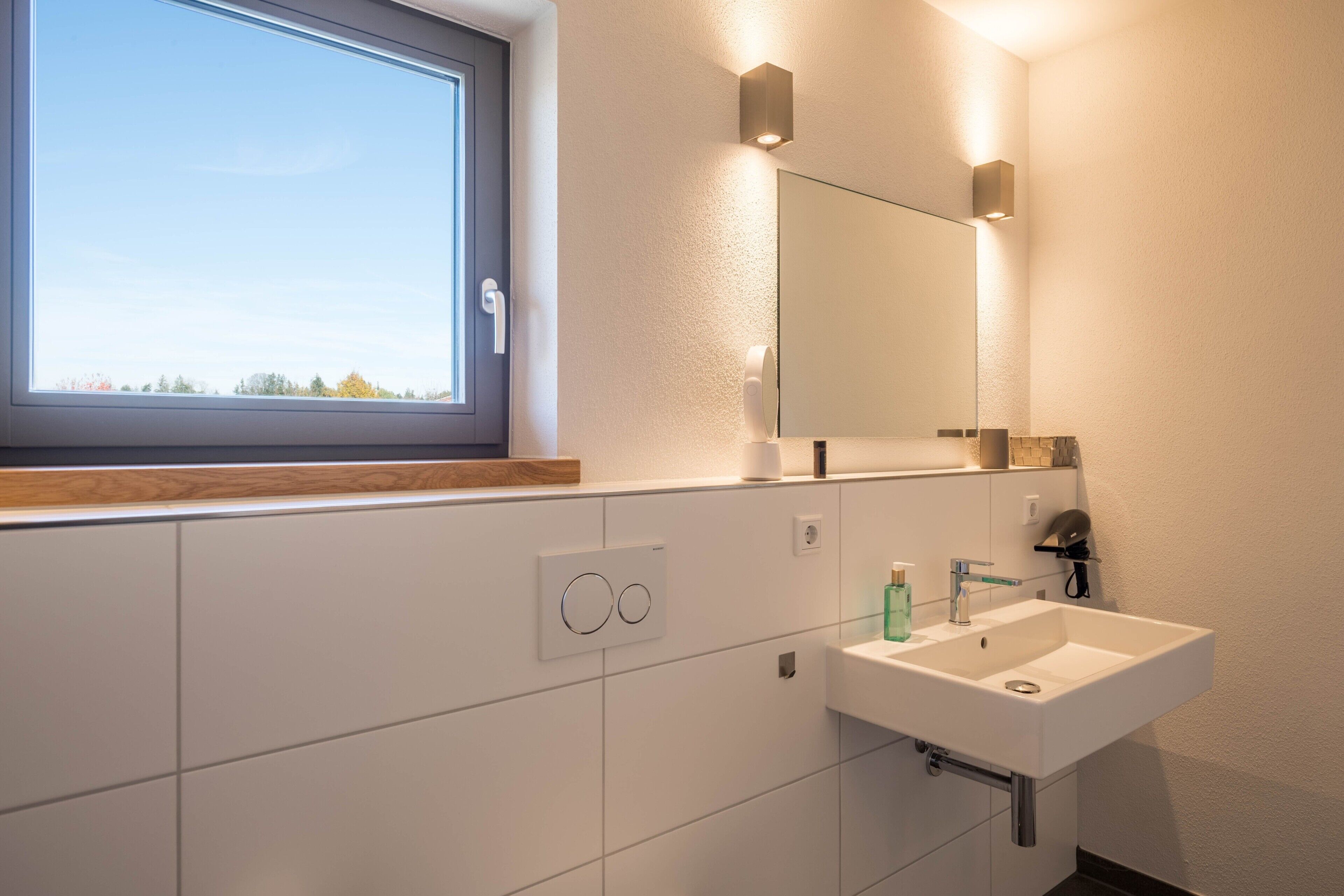 Ein modernes Badezimmer mit Fenster, Waschbecken und Spiegel.