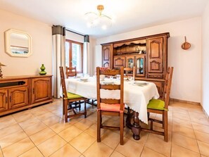 A dining area with wooden furniture, a tiled floor, and a chandelier.