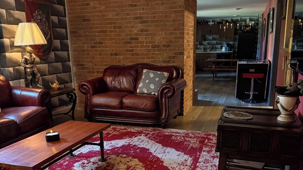 A living room with a leather sofa, a wooden coffee table, and a red patterned rug. - Harry Potter Castle (Greer)