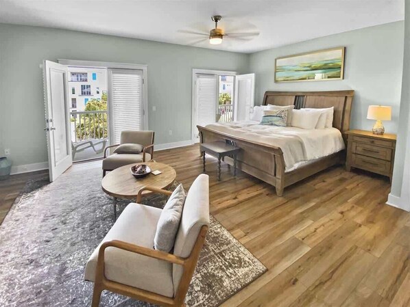 A bedroom with a bed, a nightstand, a chair, a round table, and a balcony with a view.