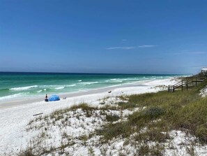 A beach with white sand, a clear blue sky, and a few tents.