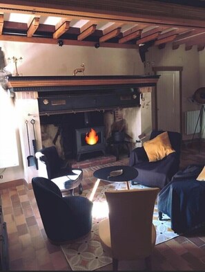 Cozy living room with a fireplace as the focal point, featuring a high ceiling and comfortable seating arrangements.