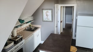 A kitchen with a dishwasher, a sink, and a refrigerator. There is a door leading to another room. - Beautiful, Cozy Condo with large private deck! (Cape May)
