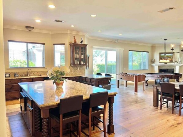 A spacious kitchen with a large island, wooden cabinets, and a dining area with a pool table. - Wine Estate - Private Pickleball, Solar Pool, Golf (Temecula)