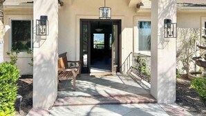 A covered porch with a bench, a door leading inside, and a view of the outdoors. - Wine Estate - Private Pickleball, Solar Pool, Golf (Temecula)