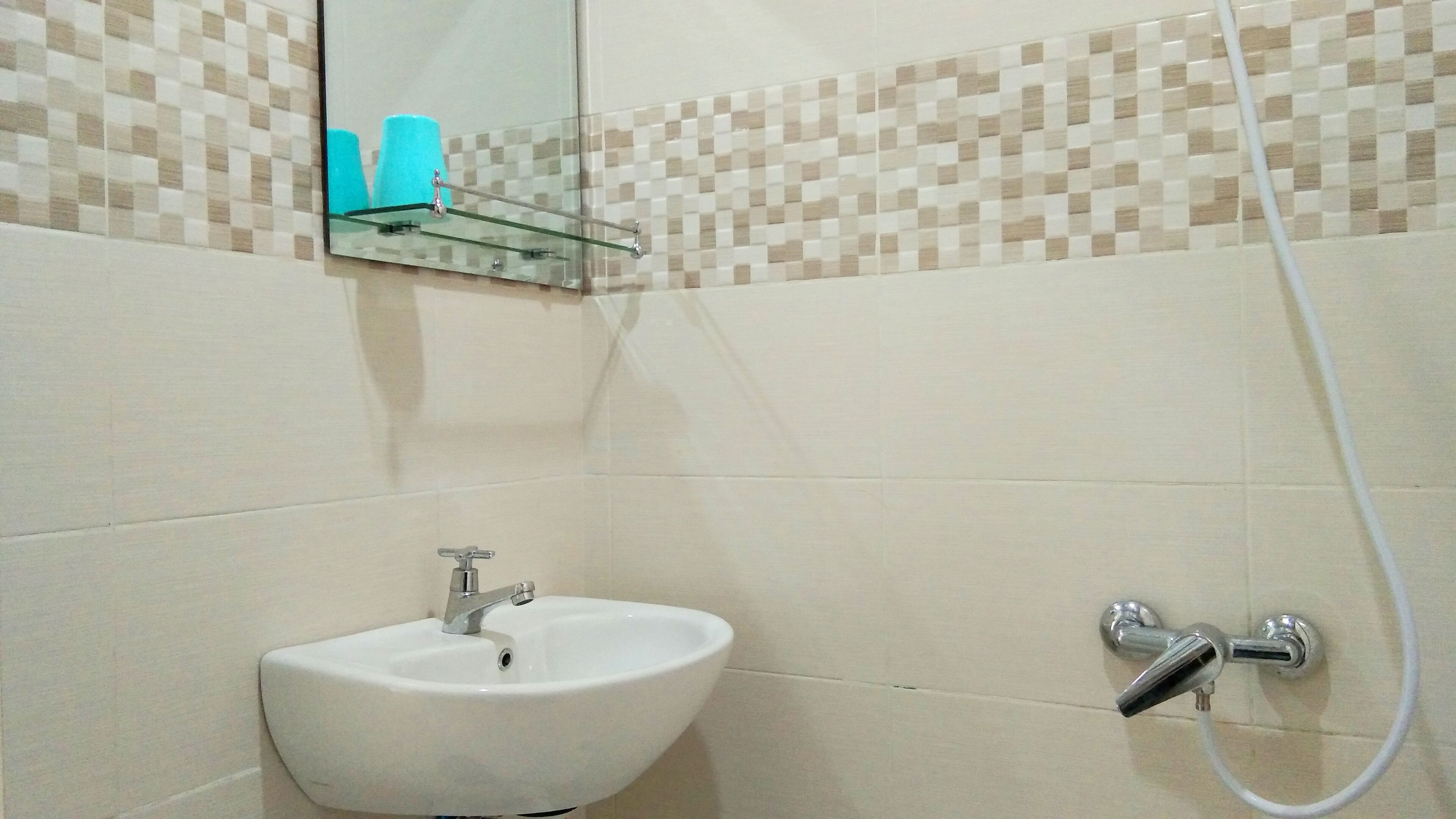 Casa de banho com uma sanita branca, espelho e chuveiro.