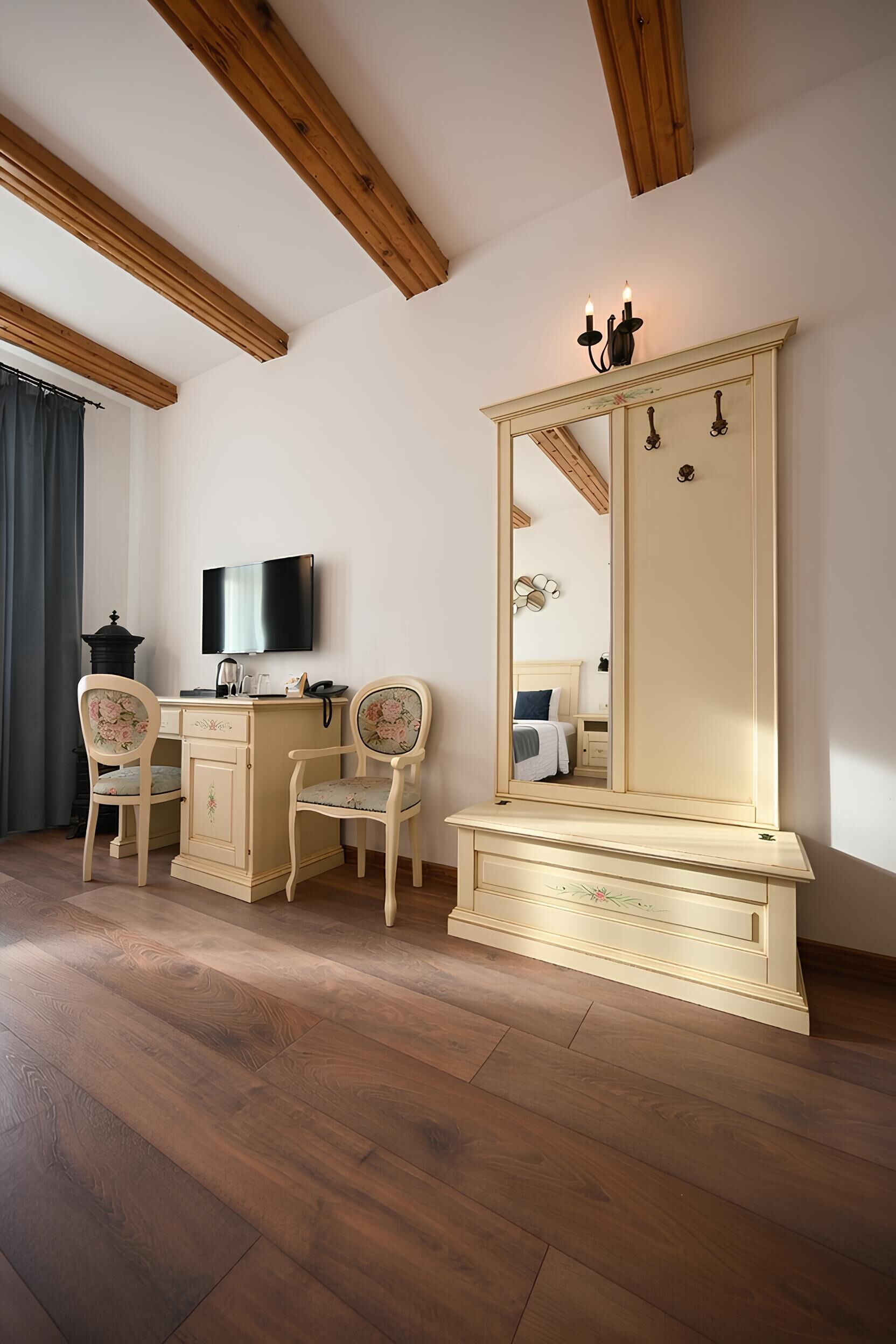 Una habitación con techo de madera, un espejo grande, un televisor y dos sillas.