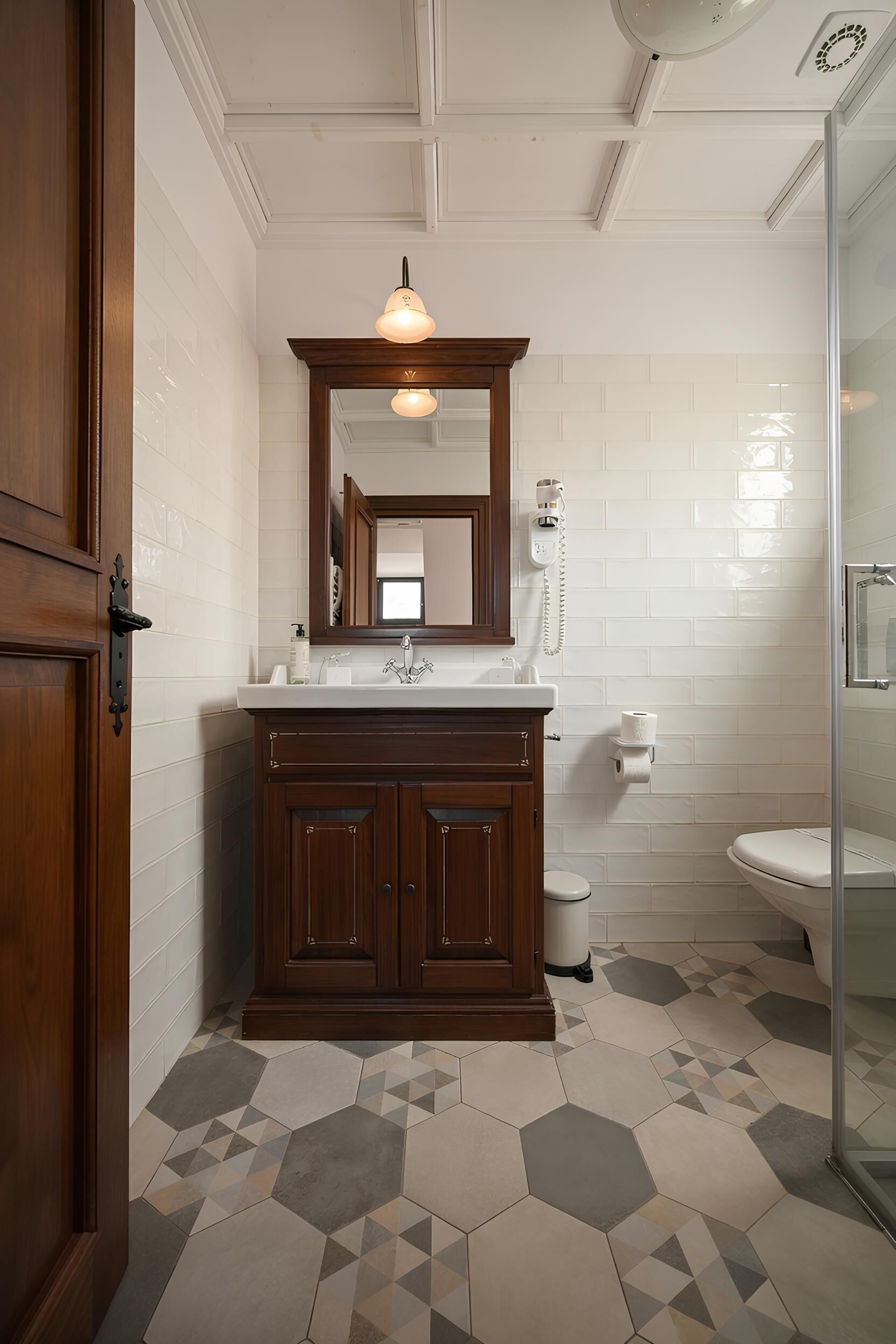 A bathroom with a wooden vanity, a mirror, a toilet, and a shower area.