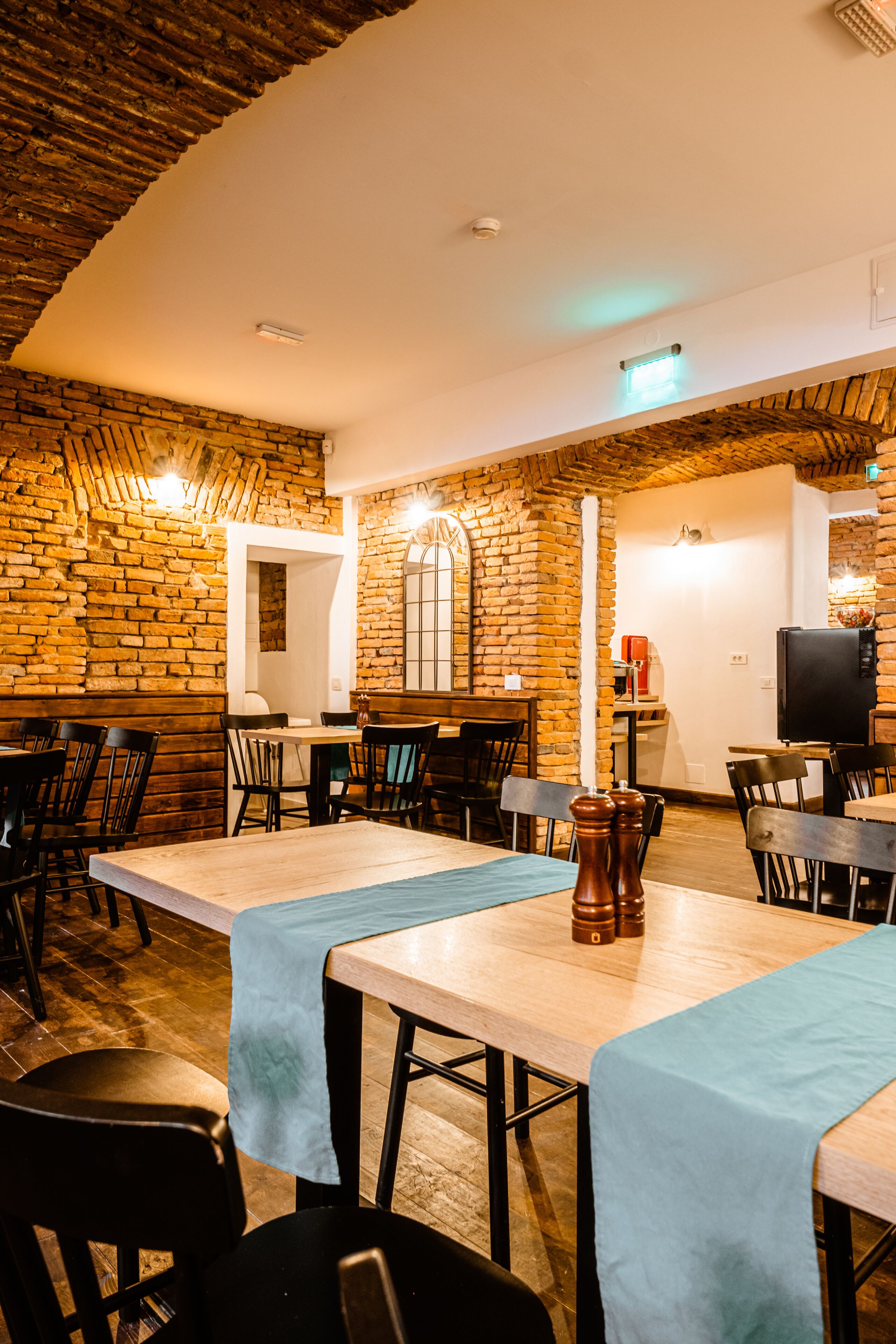 Un restaurant aux murs de briques, aux tables en bois et aux chaises noires.