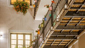 A multi-level interior with a staircase, multiple windows, and hanging planters with flowers. - Casa Chitic Hotels (Brasov)