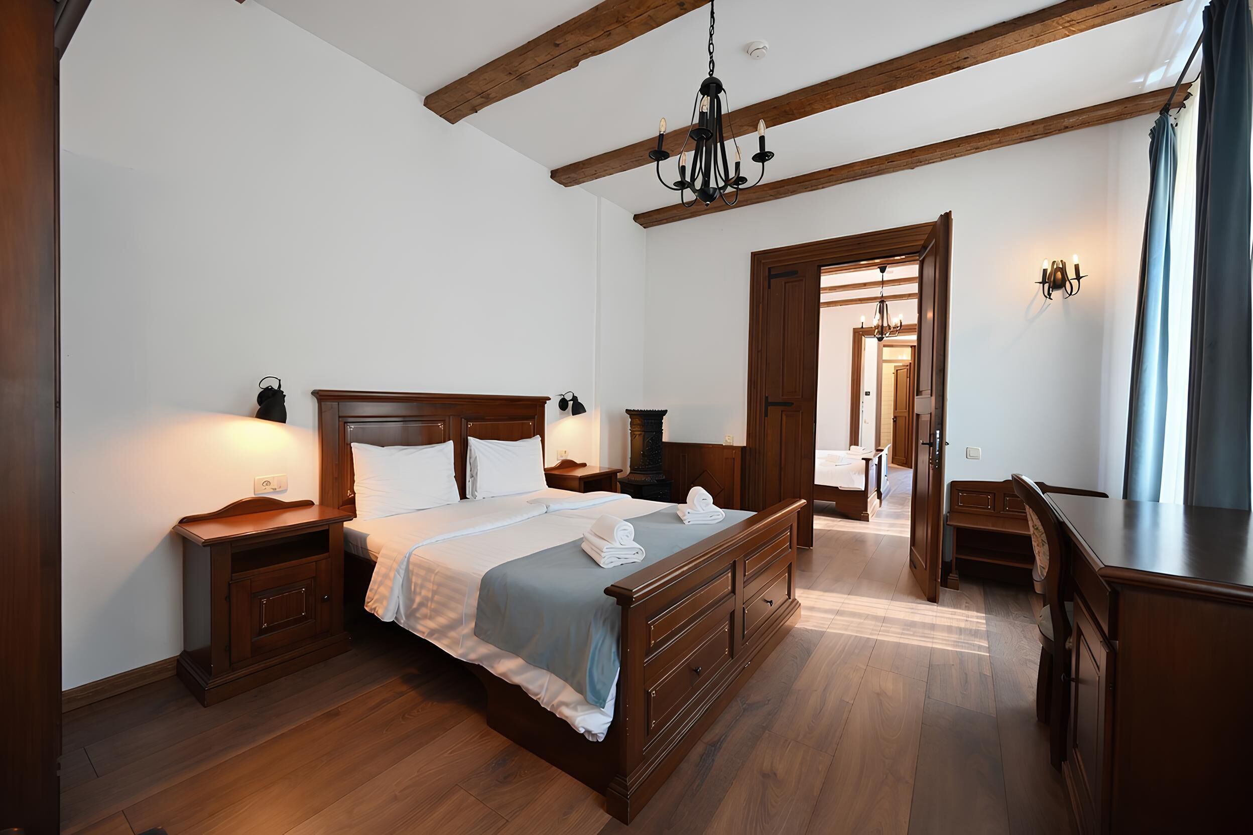 A spacious bedroom with a large bed, wooden headboard, bedside tables, and a wardrobe.