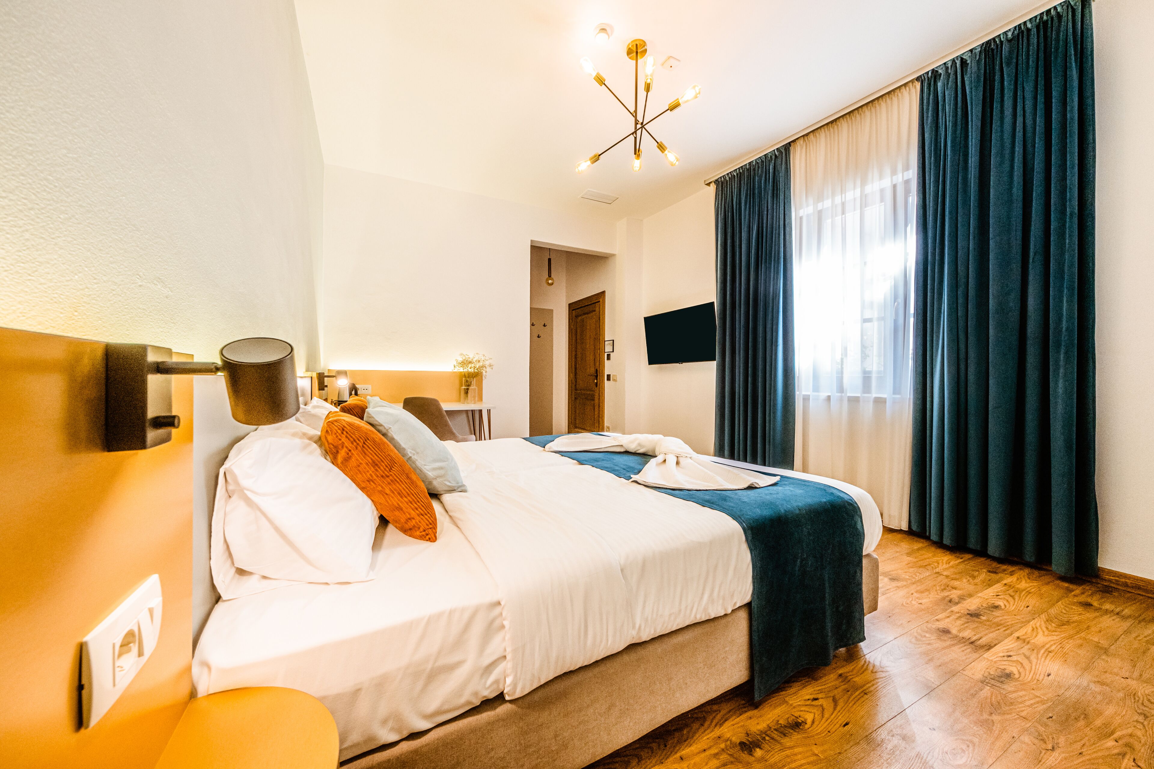 Una habitación de hotel con una cama grande, un escritorio, una silla, un televisor y un candelabro.