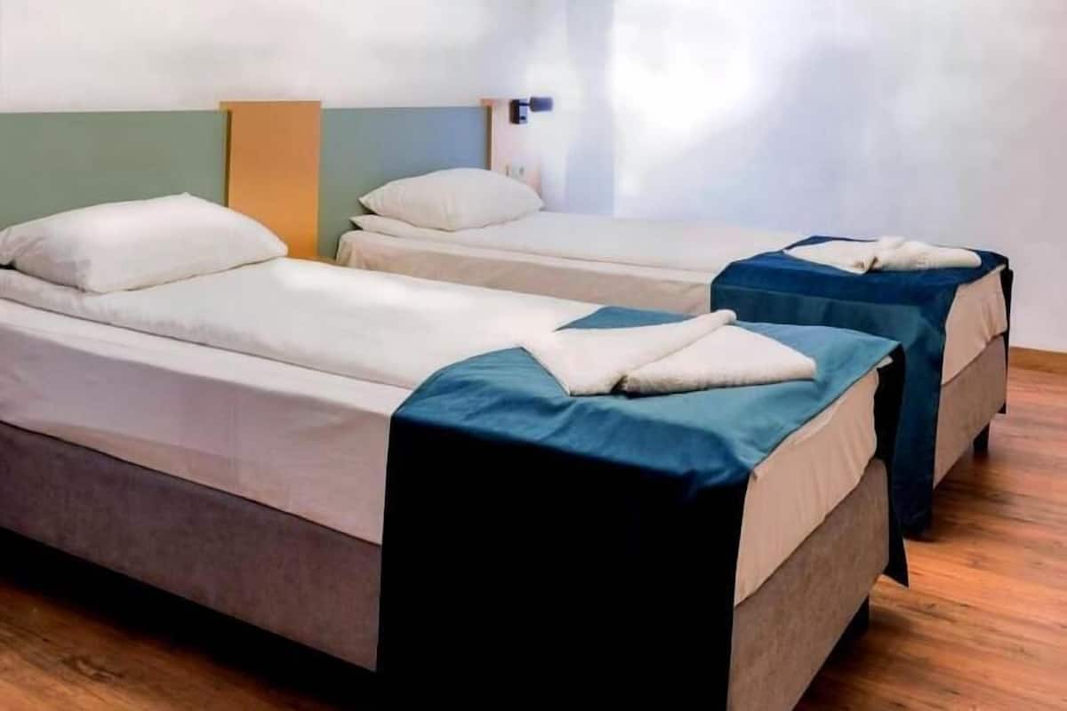 A room with two beds, a ceiling light fixture, and a window.