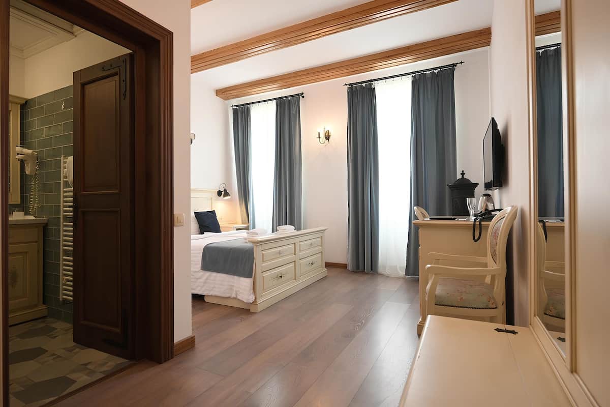 A bedroom with a bed, dresser, chair, and a television.